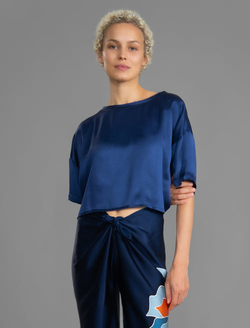 Front view. Slightly cropped boxy 100% silk stretch t-shirt in dark blue with raw cut detail on neckline and sleeves.