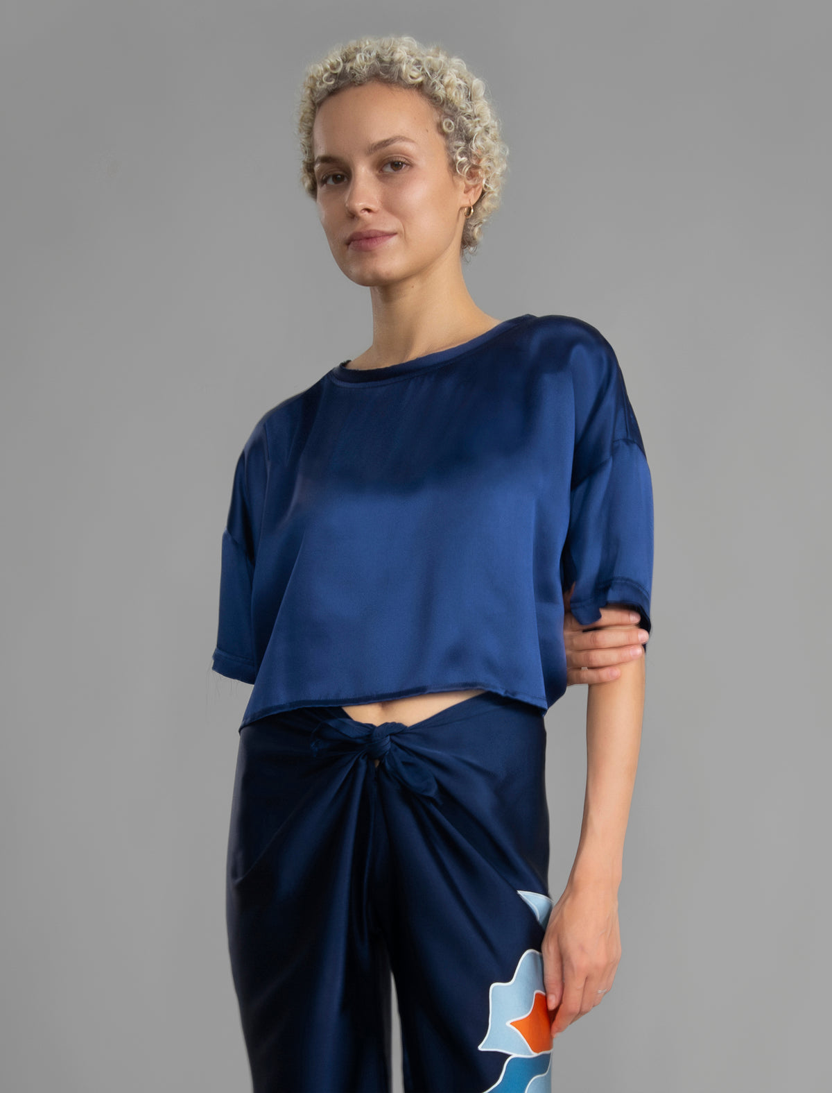 Front view. Slightly cropped boxy 100% silk stretch t-shirt in dark blue with raw cut detail on neckline and sleeves.