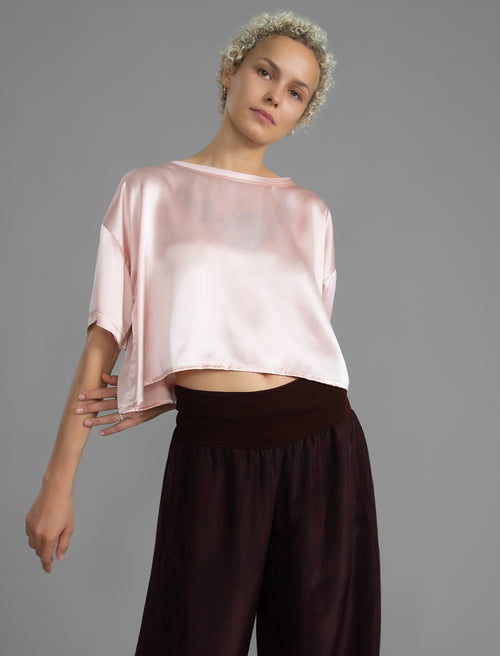 Close view. Slightly cropped boxy 100% silk stretch t-shirt in soft pink with raw cut detail on neckline and sleeves.