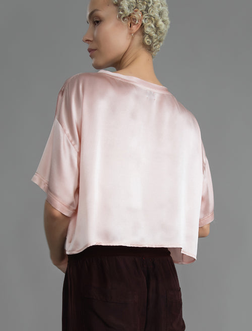 Back view. Slightly cropped boxy 100% silk stretch t-shirt in soft pink with raw cut detail on neckline and sleeves.