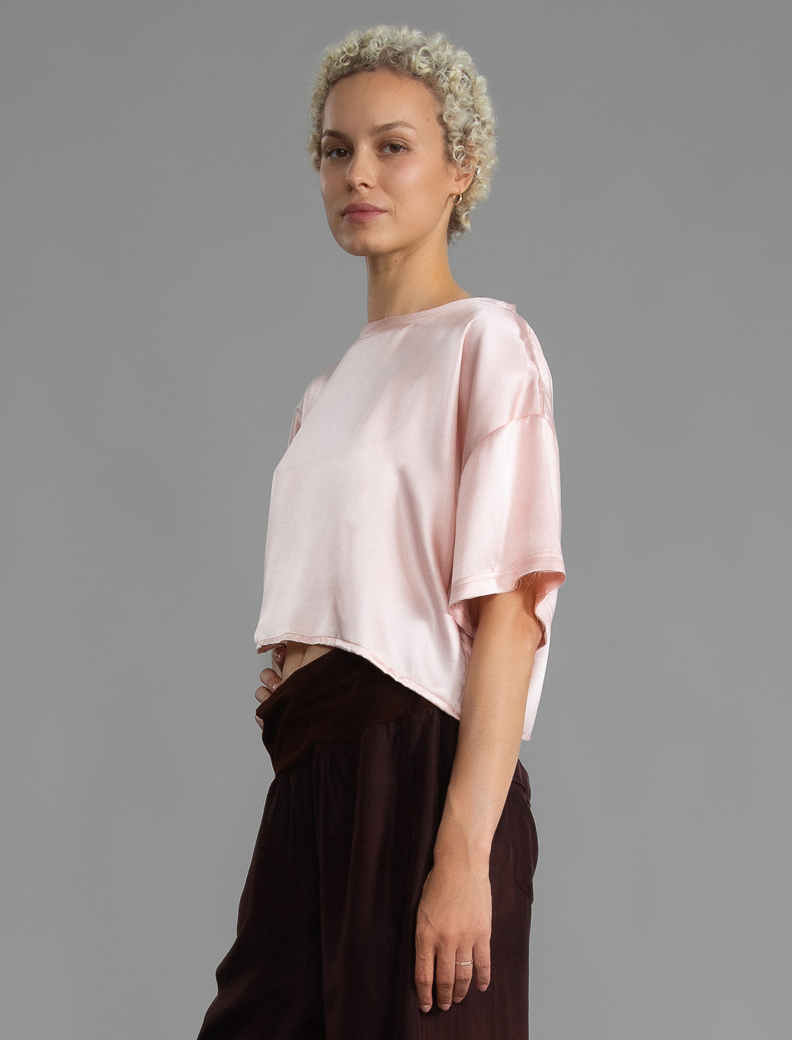 Side view. Slightly cropped boxy 100% silk stretch t-shirt in soft pink with raw cut detail on neckline and sleeves.