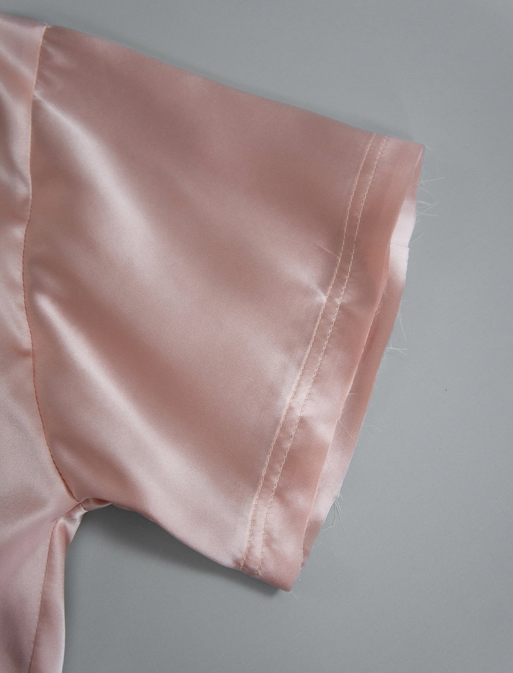 Sleeve detail. Slightly cropped boxy 100% silk stretch t-shirt in soft pink with raw cut detail on neckline and sleeves.
