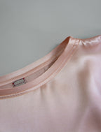 Neckline detail. Slightly cropped boxy 100% silk stretch t-shirt in soft pink with raw cut detail on neckline and sleeves.