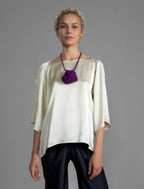 Close view. Lightweight 100% silk satin top in ivory colour, features a wide neckline with a button fastening at the back, a gently curved hemline and wide sleeves 3/4 length sleeves.