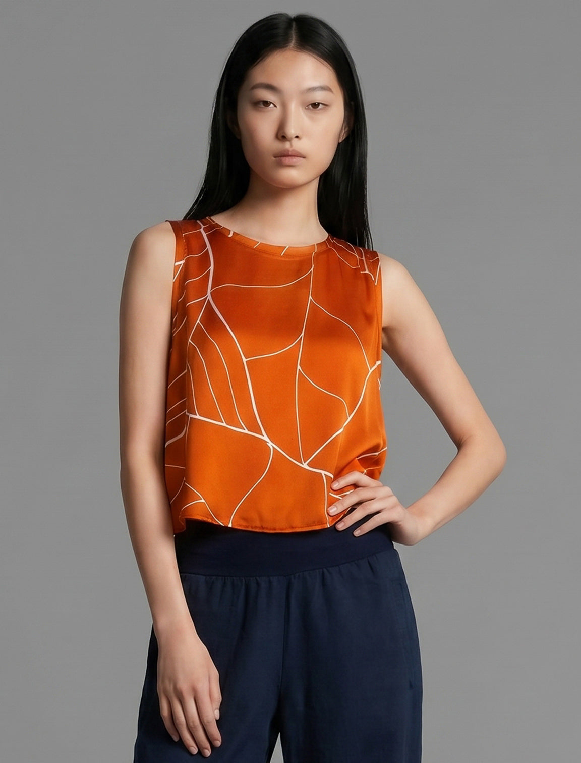 Front view. 100% silk short length stretch singlet with linear leaf motif on orange colour with open neckline and wide shoulder straps.