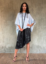 Load image into Gallery viewer, This asymmetric Skirt-Pant is handcrafted from silk satin and blur the line between shorts and skirt. A deep, gathered waistband flows into a fluid silhouette, finished with a diagonal hemline that brings an unconventional edge to refined dressing.This  hand-drawn batik motif is inspired from the late 19th-century ‘Wiener Secession’ art movement, infusing the design with a refined sense of linear rigor softened by small foliage details. here in black background and steel grey motif.
