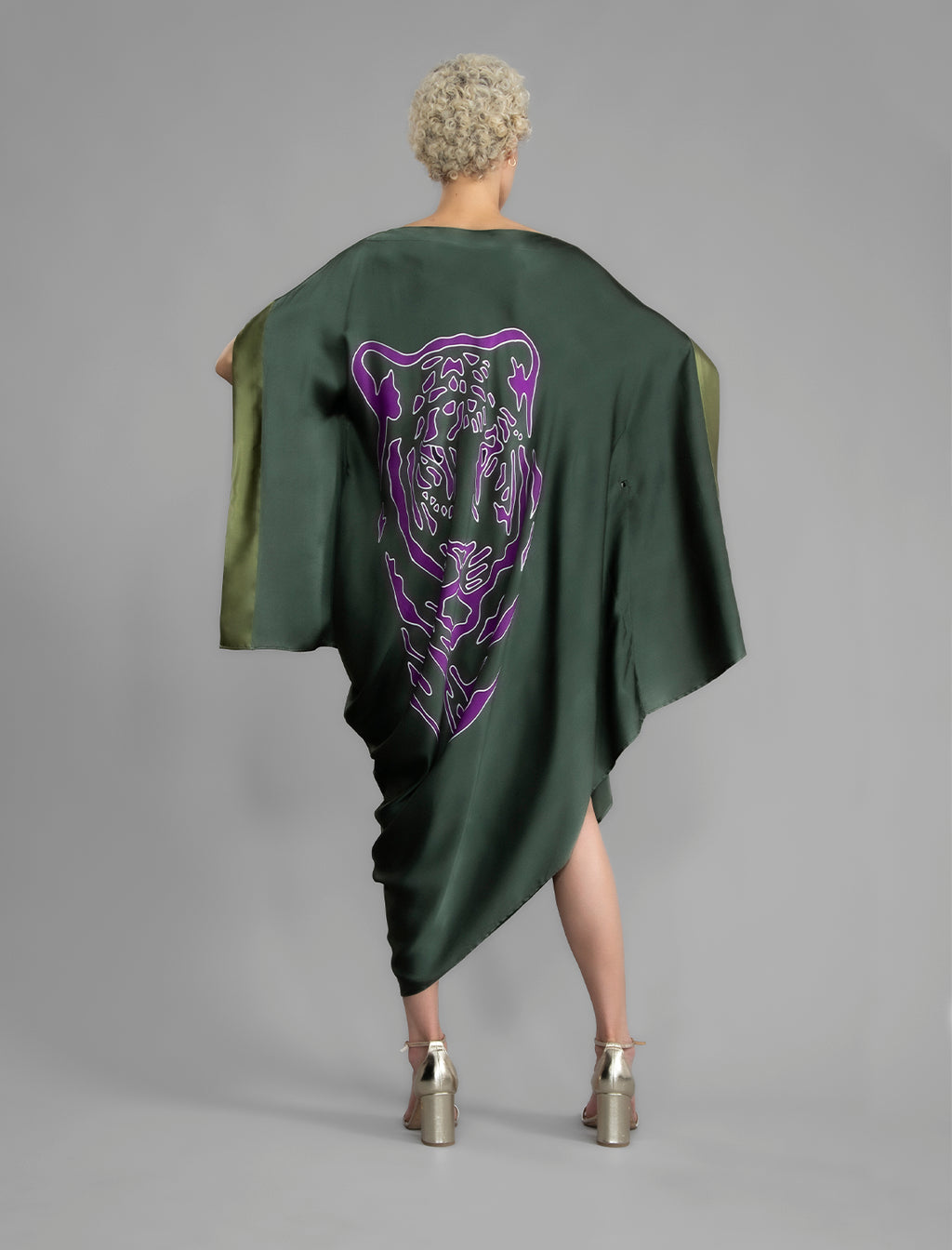 Back View. Forest green silk batik dress with bold handmade Tiger batik motif in purple, draped silhouette and artisanal craftsmanship from Bali.