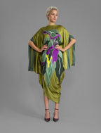 Front view. Elegant silk kaftan dress with oversized tropical leaf motif in moss green color silk, featuring flowing kimono sleeves, asymmetrical hemline, and relaxed contemporary silhouette.