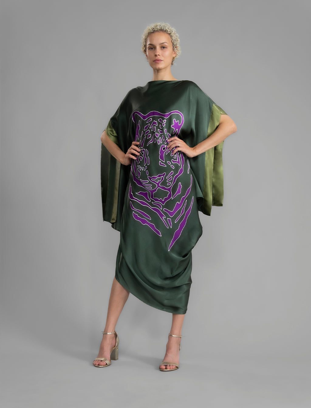 Front View. Forest green silk batik dress with bold handmade Tiger batik motif in purple, draped silhouette and artisanal craftsmanship from Bali.