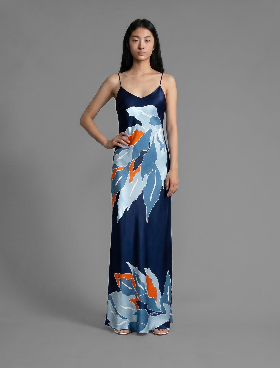 Front view. Elegant long body contouring silk dress in navy blue colour. The My Jungle motif transforms natural inspiration into contemporary elegance, featuring spaghetti straps, V-neckline and a fluid contemporary silhouette.
