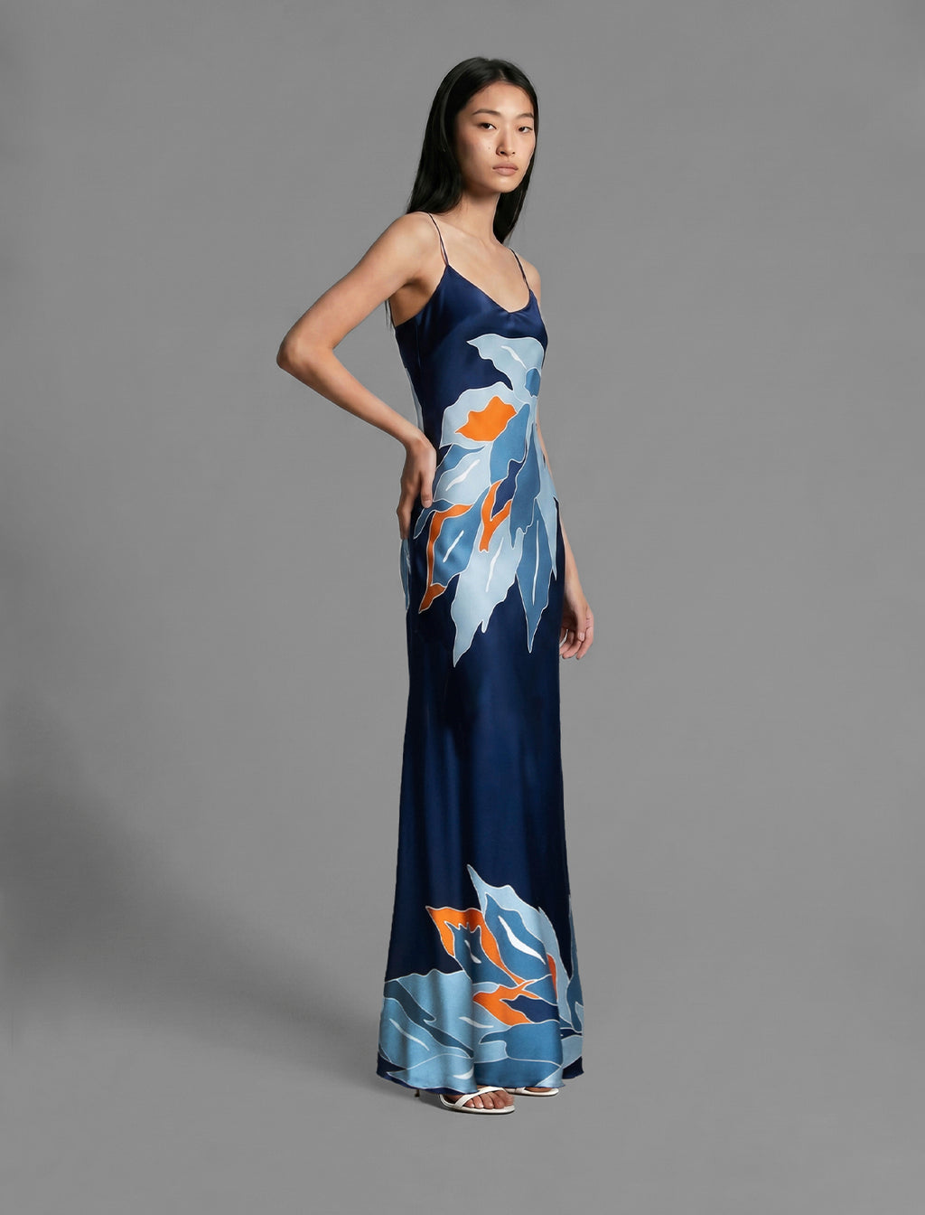 Side view. Elegant long body contouring silk dress in navy blue colour. The My Jungle motif transforms natural inspiration into contemporary elegance, featuring spaghetti straps, V-neckline and a fluid contemporary silhouette.
