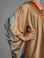 Sleeve detail. Relaxed flowing silk kaftan with graphic pale blue zebra motif on caramel colour, with orange detail, featuring 3/4 length sleeves and a voluminous silhouette.