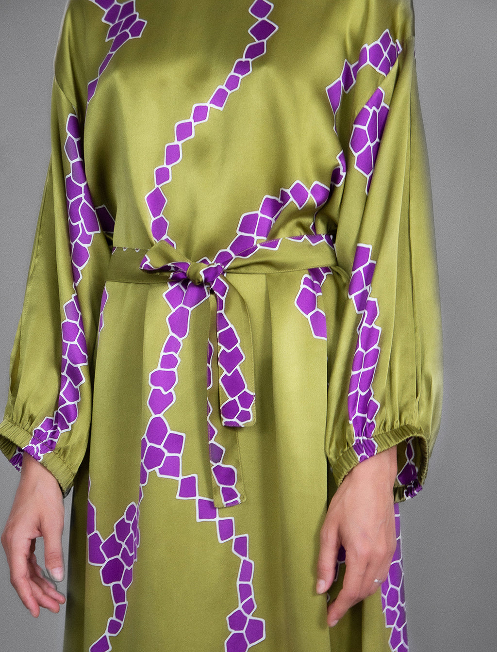 Detail view. Full length 100% silk tunic dress with purple macrosnake motif on moss green colour, featuring a open, wide neckline and one side split on the skirt, gathered 3/4 length sleeves with a slash opening and optional ribbon belt.