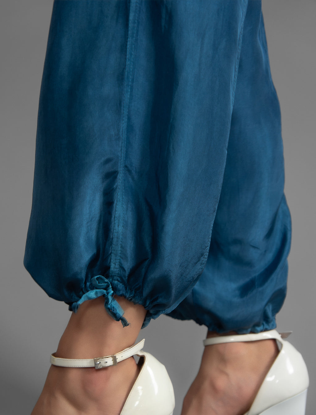 Ankle detail. Super lightweight 100% habutai silk pant in soft mid blue, with wide leg, drawstring gather at the ankle, a deep jersey waistband with a drawstring and patch pockets on the back.