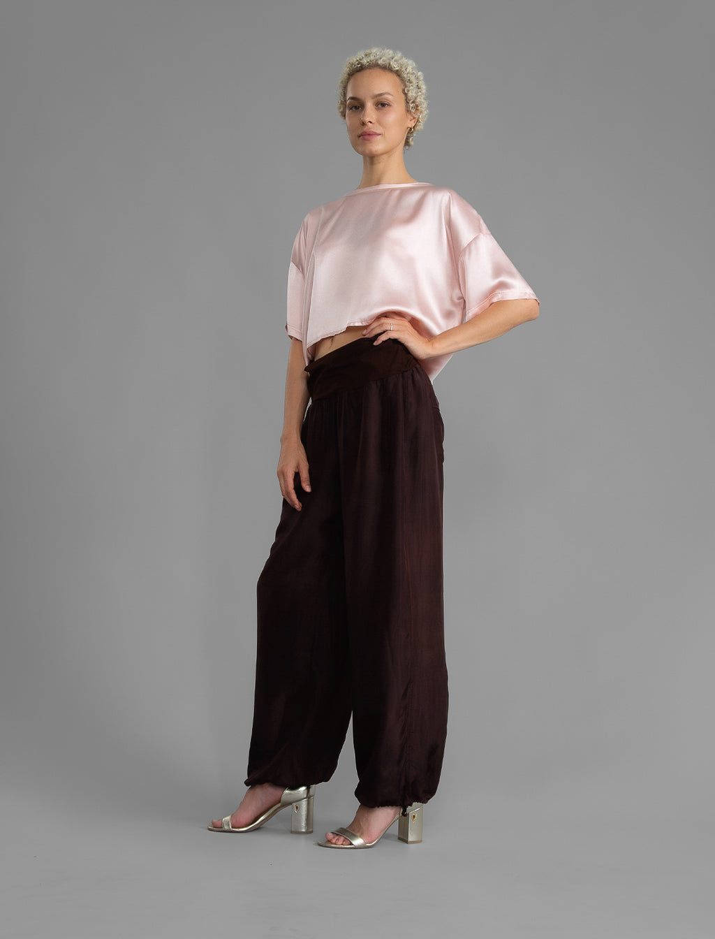 Front view. Super lightweight 100% habutai silk pant in warm brown, with wide leg, drawstring gather at the ankle, a deep jersey waistband with a drawstring and patch pockets on the back.