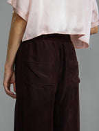 Pocket detail. Super lightweight 100% habutai silk pant in warm brown, with wide leg, drawstring gather at the ankle, a deep jersey waistband with a drawstring and patch pockets on the back.