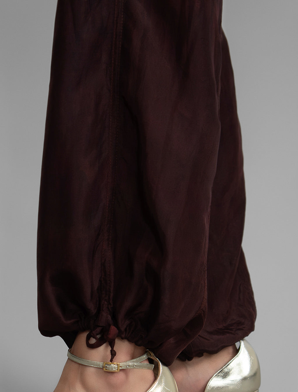 Ankle detail. Super lightweight 100% habutai silk pant in warm brown, with wide leg, drawstring gather at the ankle, a deep jersey waistband with a drawstring and patch pockets on the back.
