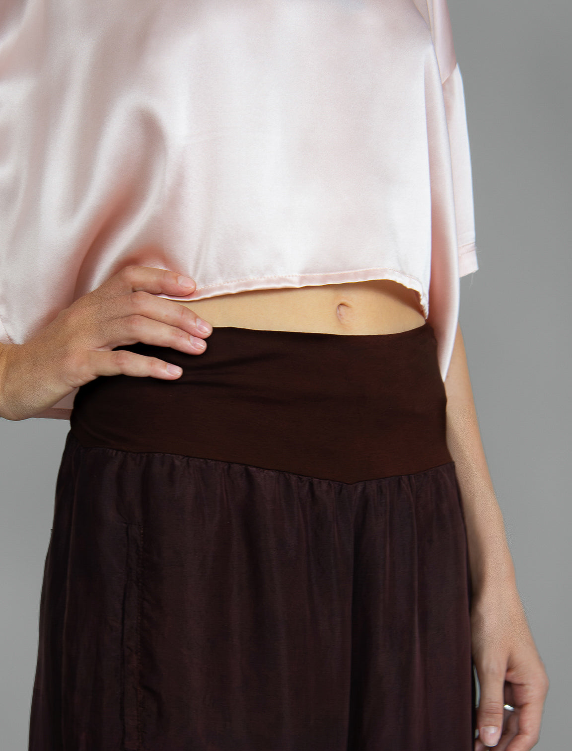 Waist detail. Super lightweight 100% habutai silk pant in warm brown, with wide leg, drawstring gather at the ankle, a deep jersey waistband with a drawstring and patch pockets on the back.