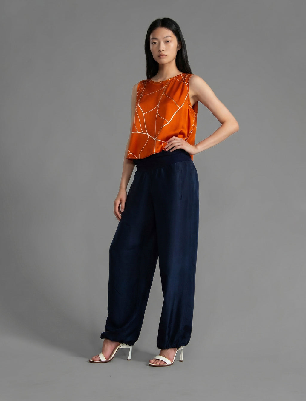 Front view. Super lightweight 100% habutai silk pant in navy blue, with wide leg, drawstring gather at the ankle, a deep jersey waistband with a drawstring and patch pockets on the back.