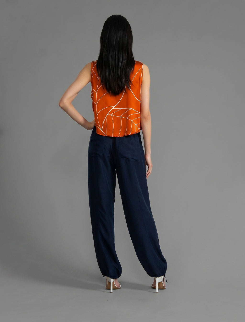 Back view. Super lightweight 100% habutai silk pant in navy blue, with wide leg, drawstring gather at the ankle, a deep jersey waistband with a drawstring and patch pockets on the back.