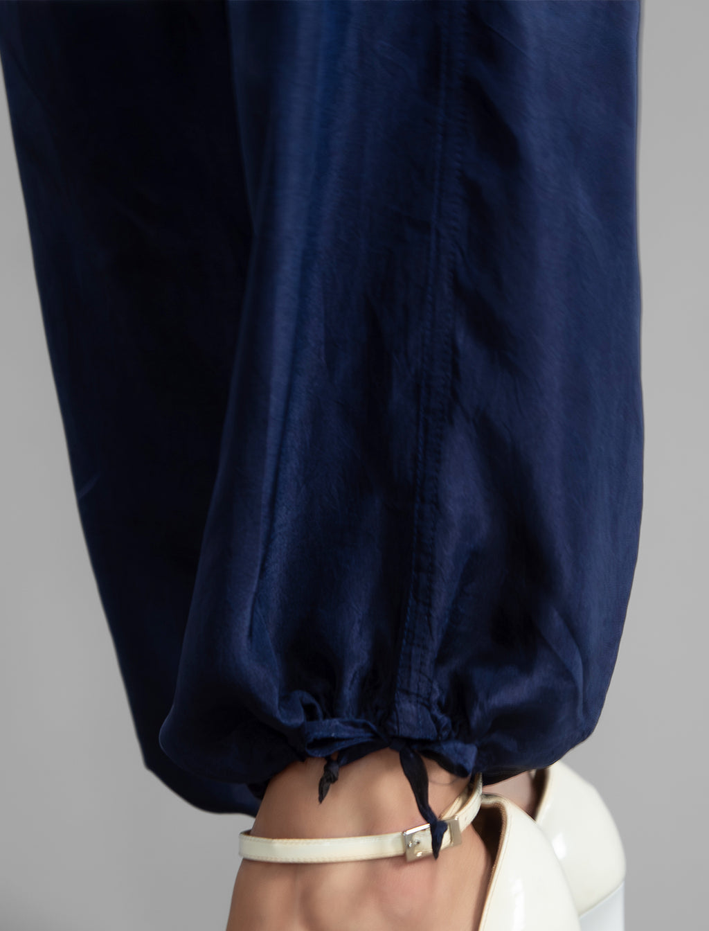 Ankle detail. Super lightweight 100% habutai silk pant in navy blue, with wide leg, drawstring gather at the ankle, a deep jersey waistband with a drawstring and patch pockets on the back.