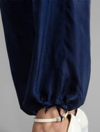 Ankle detail. Super lightweight 100% habutai silk pant in navy blue, with wide leg, drawstring gather at the ankle, a deep jersey waistband with a drawstring and patch pockets on the back.