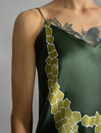 Strap and neckline detail: Elegant long body contouring silk dress in forest green colour with contrasting green graphic Macrosnake batik motif, featuring spaghetti straps, V-neckline and a fluid contemporary silhouette.