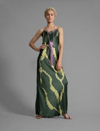 Front view. Elegant long body contouring silk dress in forest green colour with contrasting green graphic Macrosnake batik motif, featuring spaghetti straps, V-neckline and a fluid contemporary silhouette.