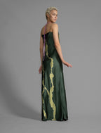 Side view. Elegant long body contouring silk dress in forest green colour with contrasting green graphic Macrosnake batik motif, featuring spaghetti straps, V-neckline and a fluid contemporary silhouette.