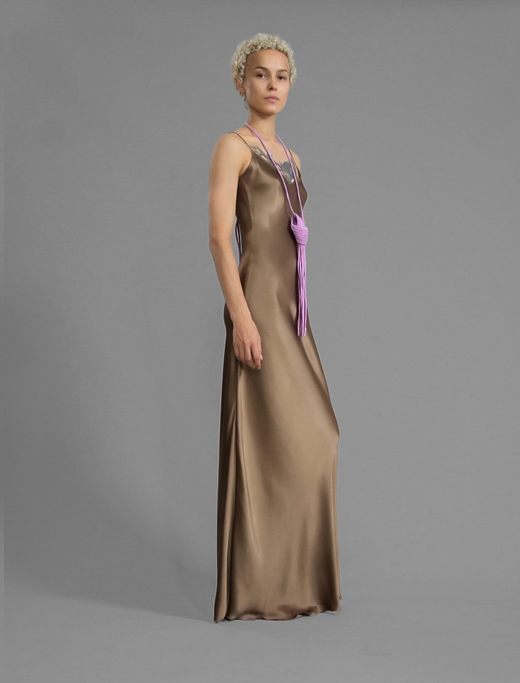 Side view. Elegant long body contouring silk dress in soft mocha colour, featuring spaghetti straps, V-neckline and a fluid contemporary silhouette.