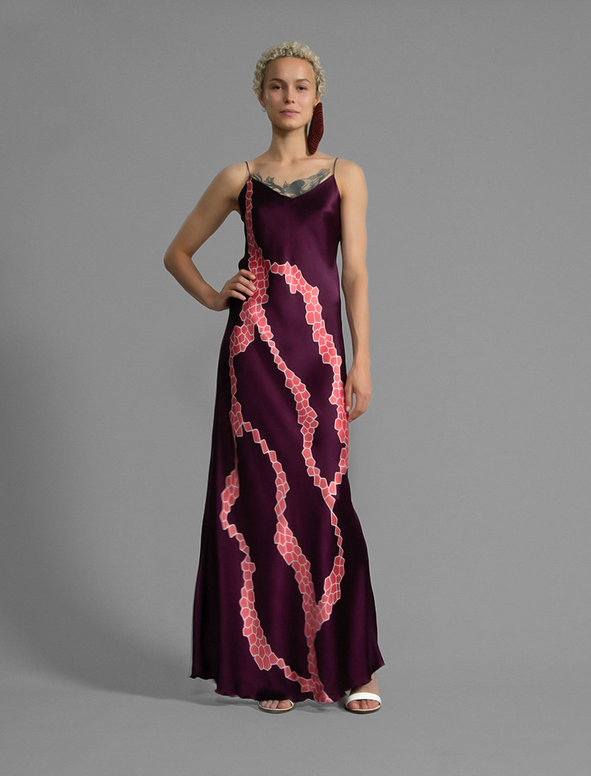 Front View. Elegant long body contouring silk dress in deep vino colour with contrasting pink graphic Macrosnake batik motif, featuring spaghetti straps, V-neckline and a fluid contemporary silhouette.