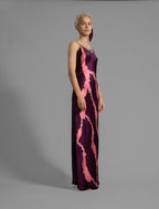 Side View. Elegant long body contouring silk dress in deep vino colour with contrasting pink graphic Macrosnake batik motif, featuring spaghetti straps, V-neckline and a fluid contemporary silhouette.