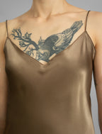Strap and neckline detail: Elegant long body contouring silk dress in soft mocha colour, featuring spaghetti straps, V-neckline and a fluid contemporary silhouette.