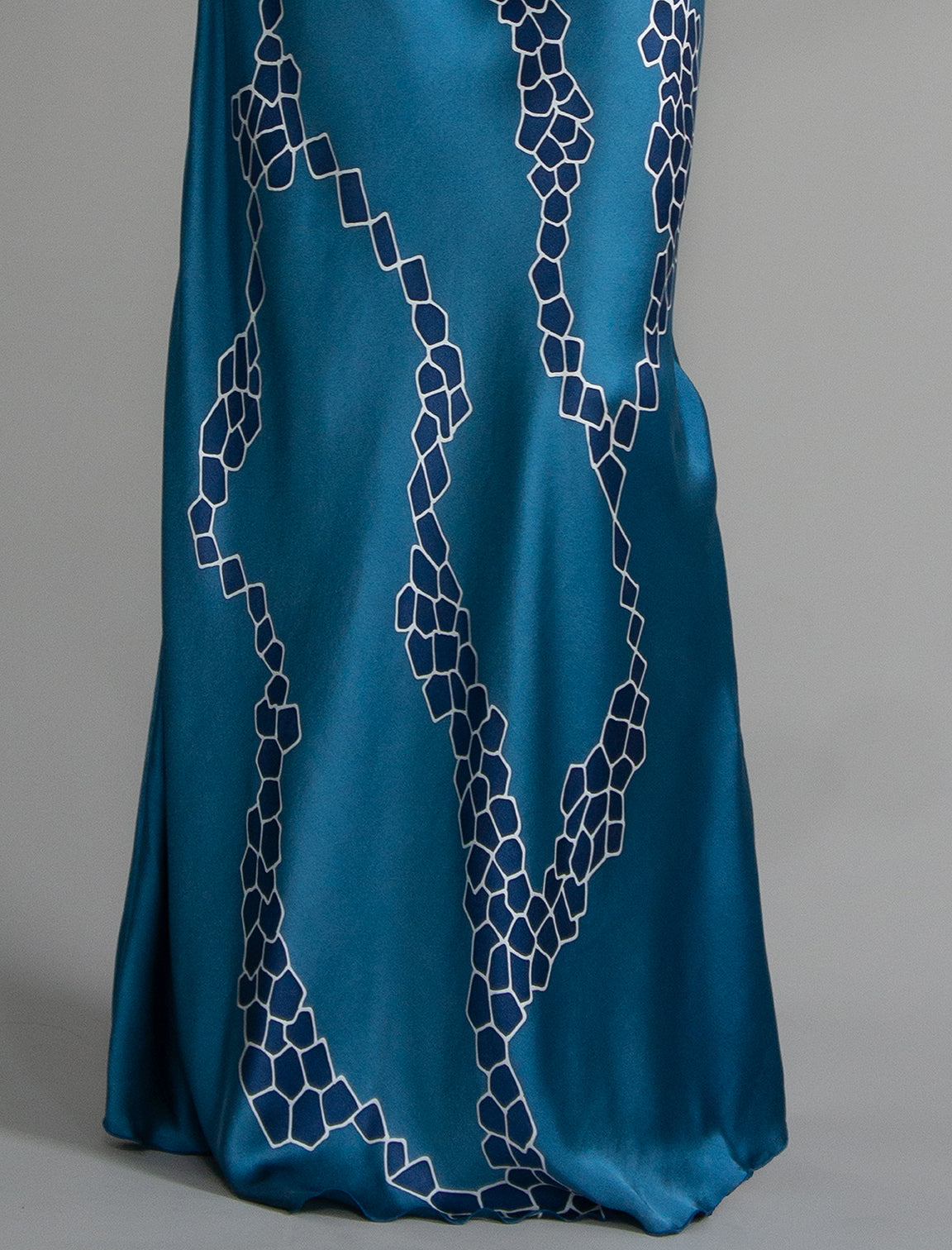 Motif detail: Elegant long body contouring silk dress in saxony blue colour with contrasting blue graphic Macrosnake batik motif, featuring spaghetti straps, V-neckline and a fluid contemporary silhouette.