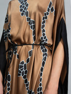 Waist detail: Elegant silk draped dress with graphic Macrosnake batik motif in black on warm tobacco colour, featuring fluid kimono sleeves, asymmetrical hemline, and relaxed contemporary silhouette with waist tie detail.