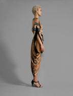 Right side view. Elegant silk draped dress with graphic Macrosnake batik motif in black on warm tobacco colour, featuring fluid kimono sleeves, asymmetrical hemline, and relaxed contemporary silhouette with waist tie detail.