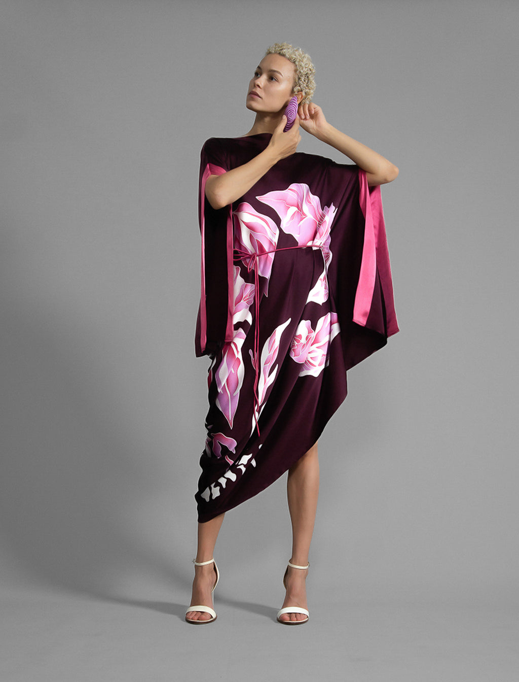 Front view 1. Elegant silk kaftan dress with oversized pink floral batik motif on deep vino colour silk, featuring flowing kimono sleeves, asymmetrical hemline, and relaxed contemporary silhouette.