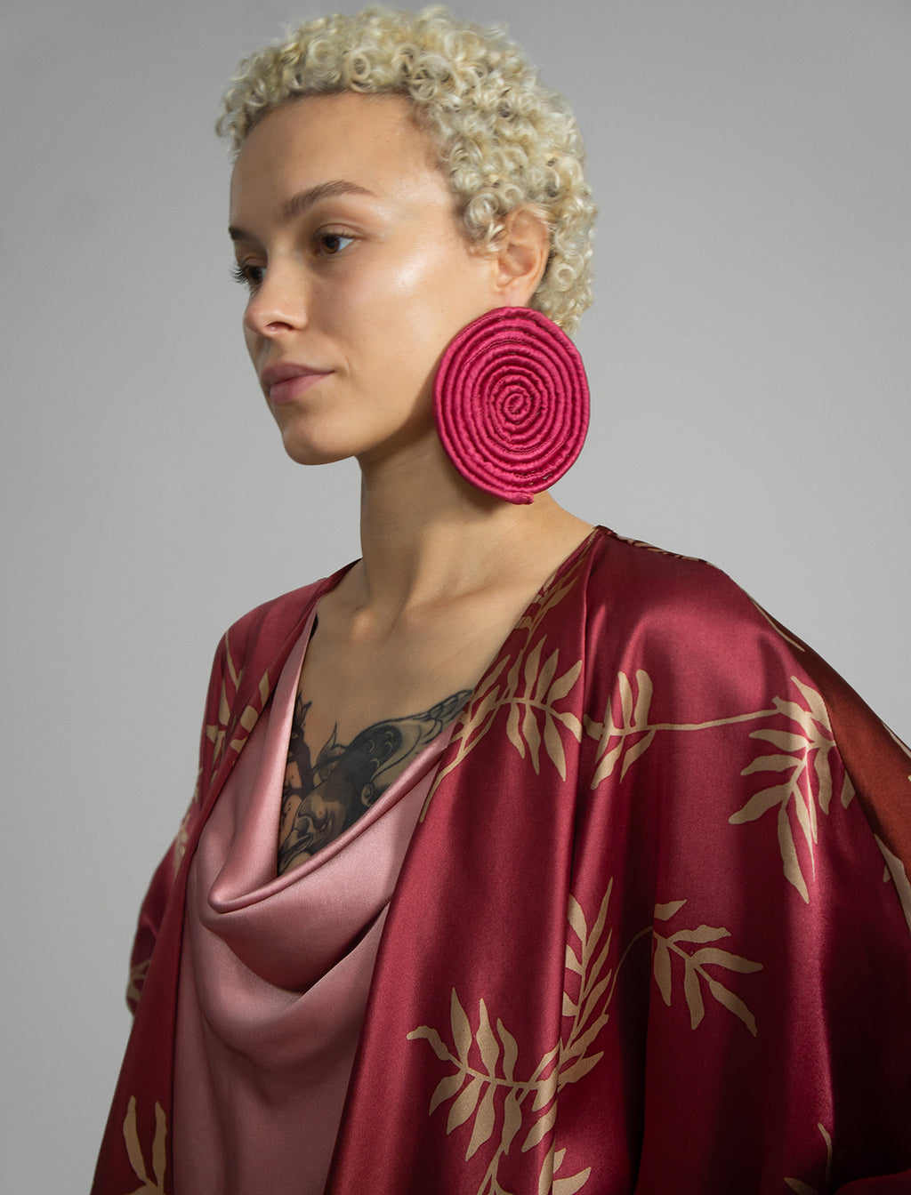 Neck detail: Relaxed flowing silk kaftan with subtle Dedaun leaf motif in russet and raspberry colour, featuring 3/4 length sleeves and a voluminous silhouette.