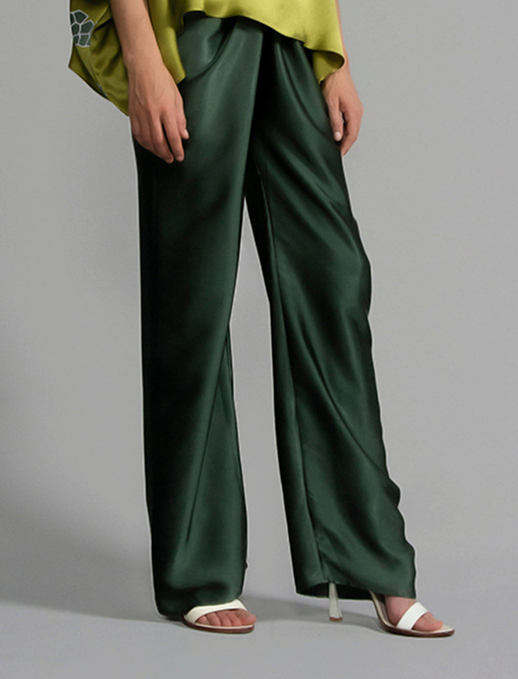 Close front view. Long silk pants in black forest green colour, featuring a knot tie at the front and a slick relaxed silhouette. 