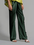 Close front view. Long silk pants in black forest green colour, featuring a knot tie at the front and a slick relaxed silhouette. 