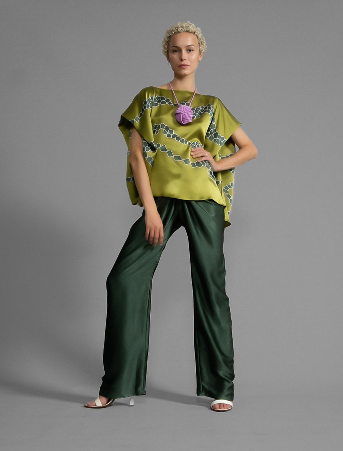 Front view. Long silk pants in black forest green colour, featuring a knot tie at the front and a slick relaxed silhouette. 