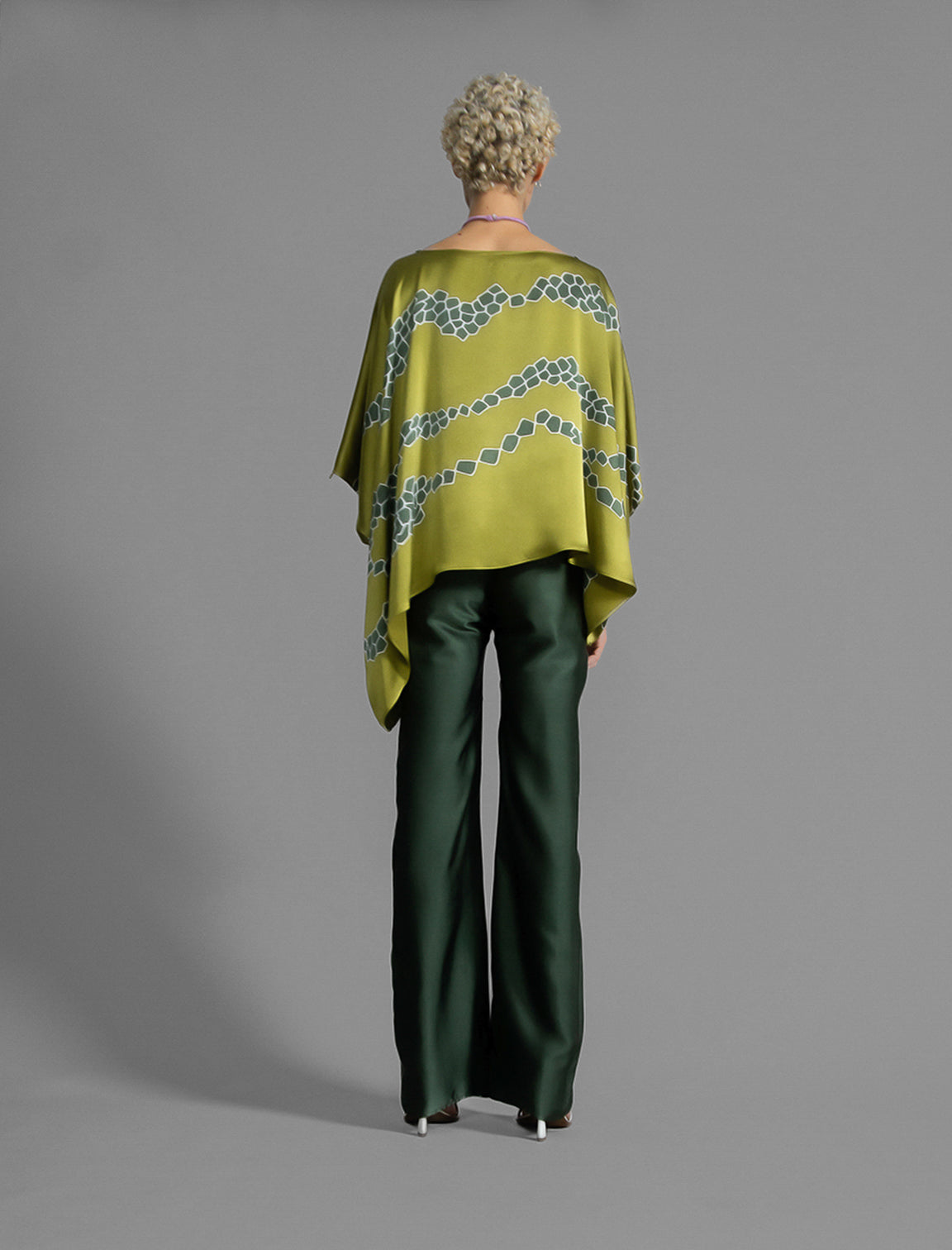 Back view. Long silk pants in black forest green colour, featuring a knot tie at the front and a slick relaxed silhouette. 