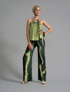 Front view. Long silk pants in forest green colour with contrasting blue graphic Macrosnake batik motif, featuring a knot tie at the front and a slick relaxed silhouette. 
