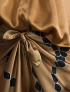 Knot detail. Long silk pants in tobacco colour with contrasting blue graphic Macrosnake batik motif, featuring a knot tie at the front and a slick relaxed silhouette. 