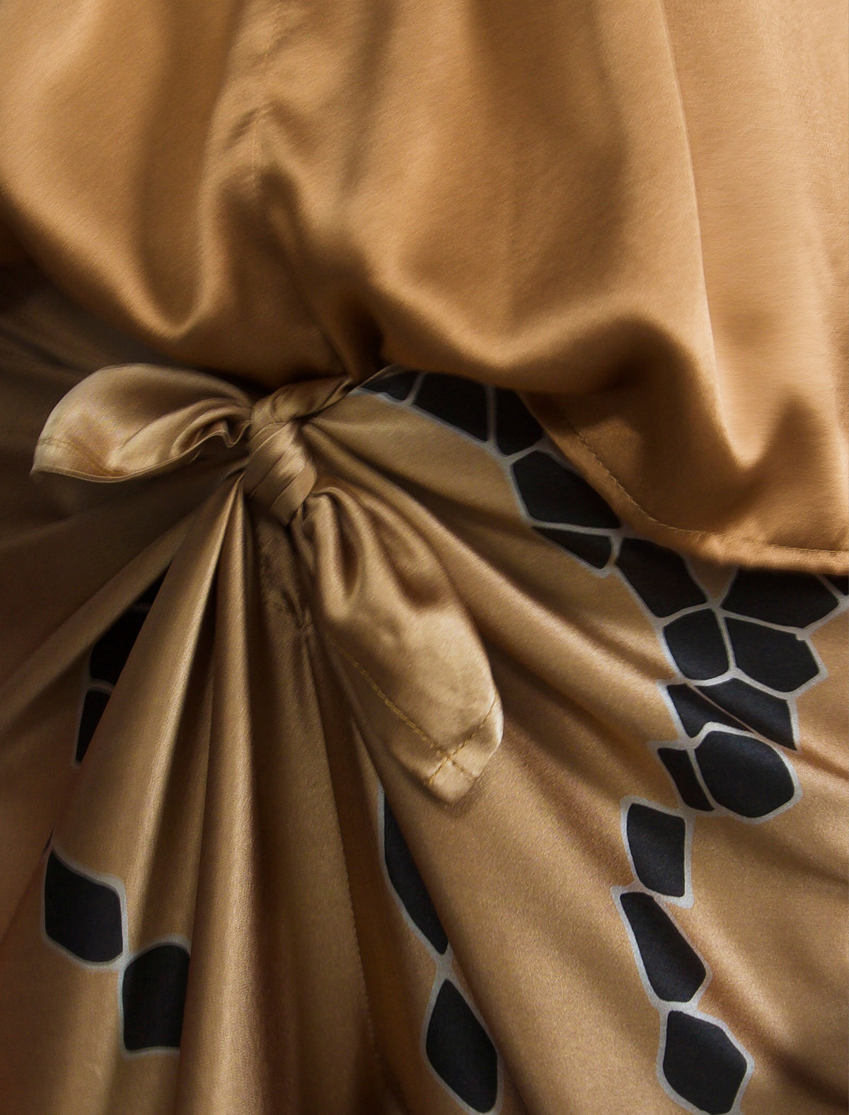 Knot detail. Long silk pants in tobacco colour with contrasting blue graphic Macrosnake batik motif, featuring a knot tie at the front and a slick relaxed silhouette. 
