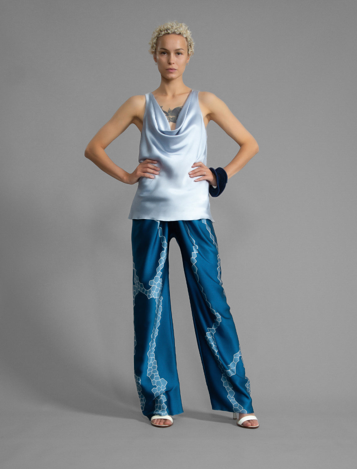 Front view. Long silk pants in saxony blue colour with contrasting blue graphic Macrosnake batik motif, featuring a knot tie at the front and a slick relaxed silhouette. 