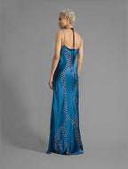 Back view. Elegant long body contouring silk dress in saxony blue colour with contrasting blue graphic Macrosnake batik motif, featuring spaghetti straps, V-neckline and a fluid contemporary silhouette.