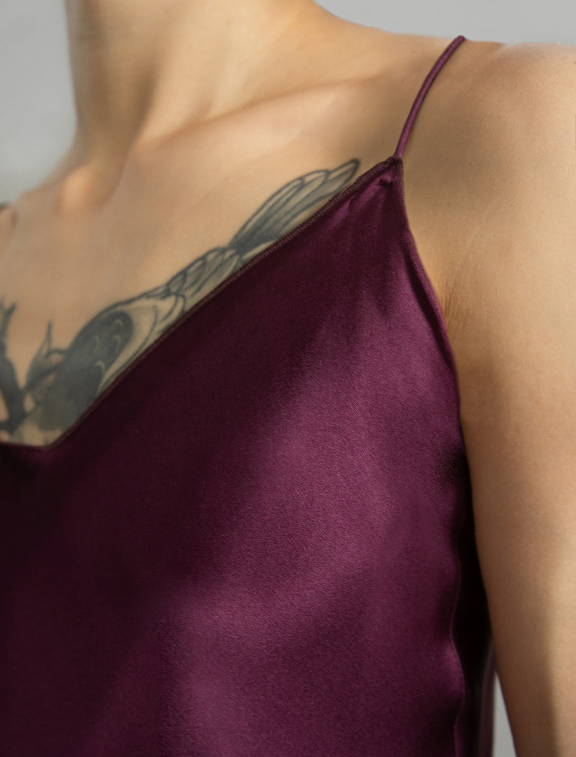 Strap and neck detail: Elegant long body contouring silk dress in deep vino colour with contrasting pink graphic Macrosnake batik motif, featuring spaghetti straps, V-neckline and a fluid contemporary silhouette.