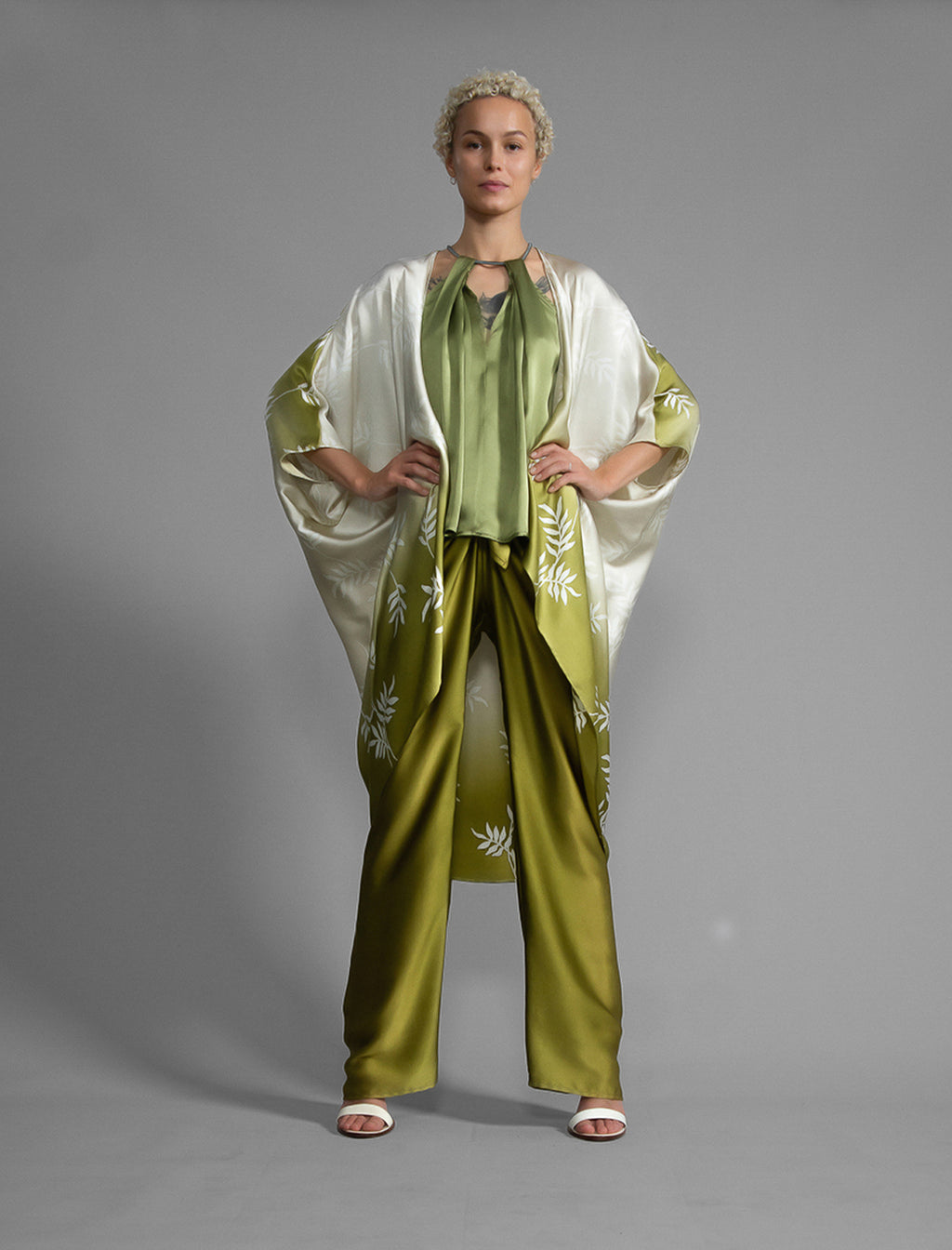 Front view. Relaxed flowing silk kaftan with subtle Dedaun leaf motif in moss green and white colour, featuring 3/4 length sleeves and a voluminous silhouette.