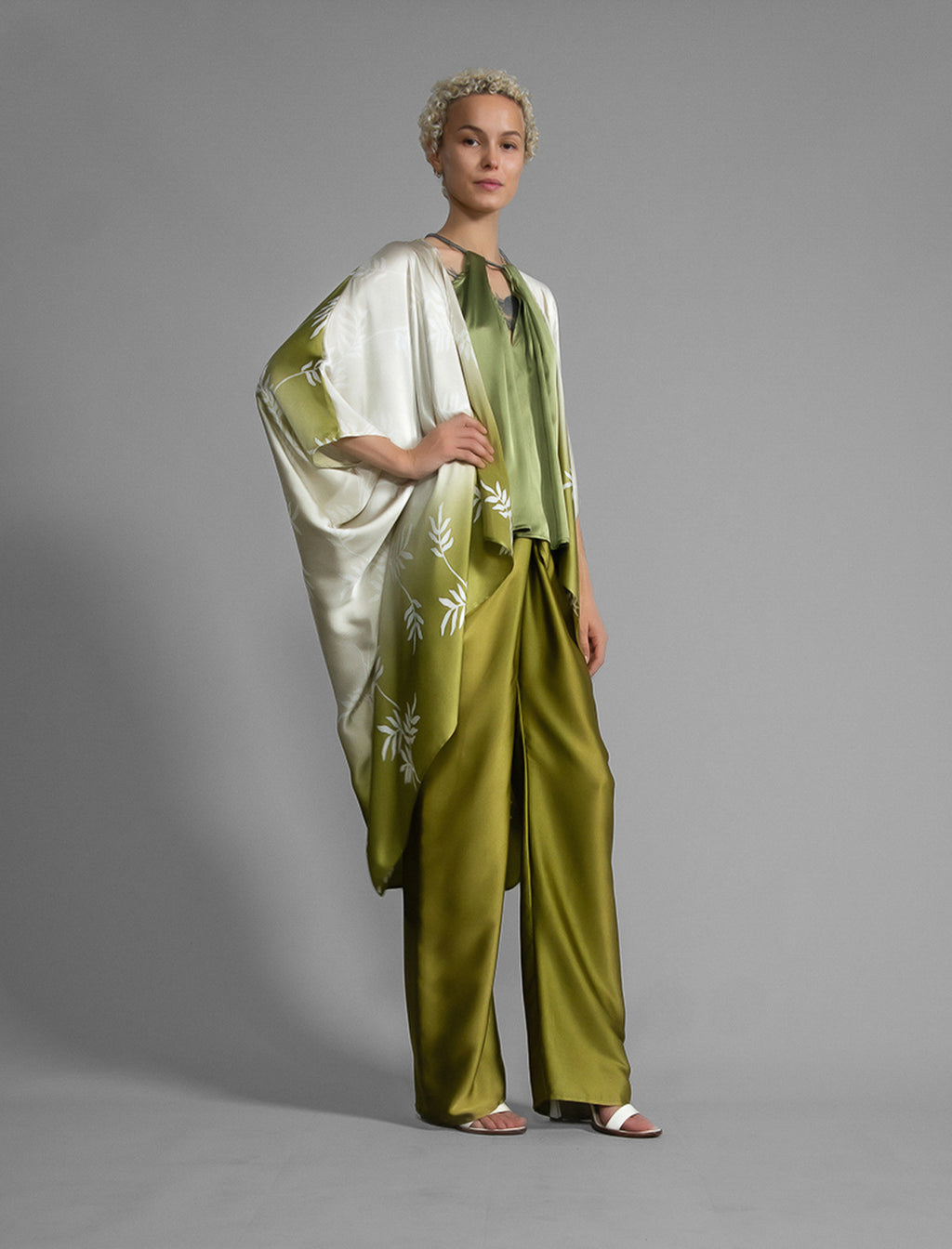 Right side. Relaxed flowing silk kaftan with subtle Dedaun leaf motif in moss green and white colour, featuring 3/4 length sleeves and a voluminous silhouette.